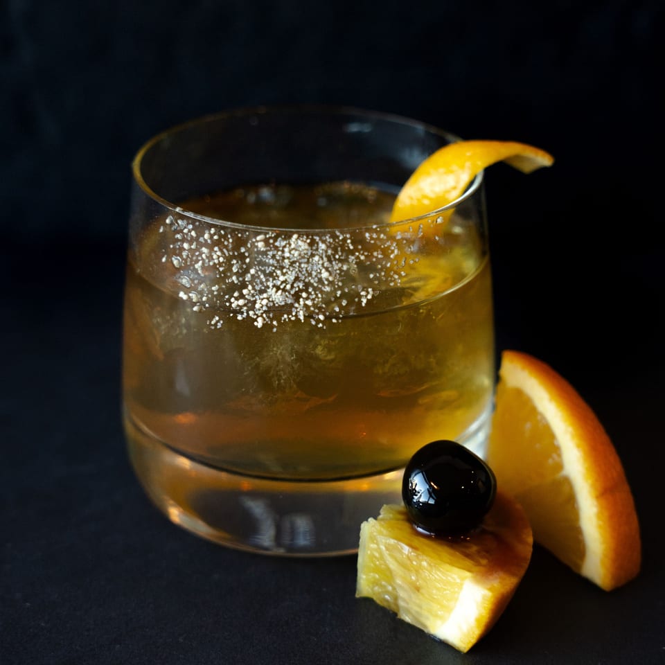 Rivage Oak Kitchen's cocktail with an orange peel, sugar rim, and a cherry on an orange slice.