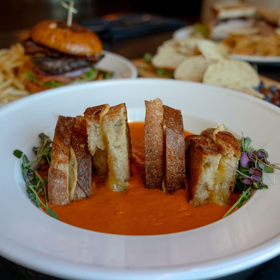 Grilled cheese croutons with microgreens in a bowl of tomato soup at Rivage Oak Kitchen.