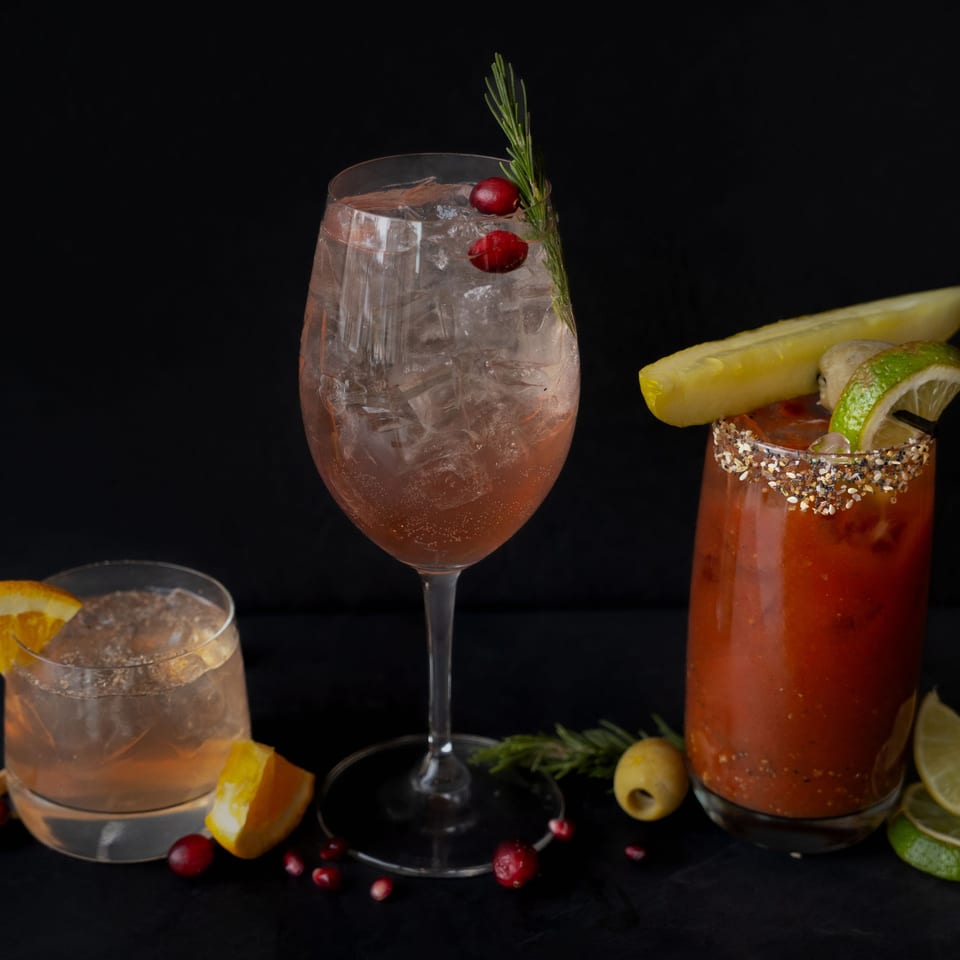 Three Rivage Oak Kitchen cocktails: a tall cranberry-rosemary drink, an old fashioned, and a Bloody Mary.